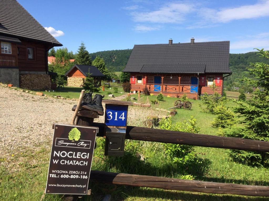 ein Holzhaus mit einem Schild davor in der Unterkunft Buczynowe Chaty in Wysowa-Zdrój