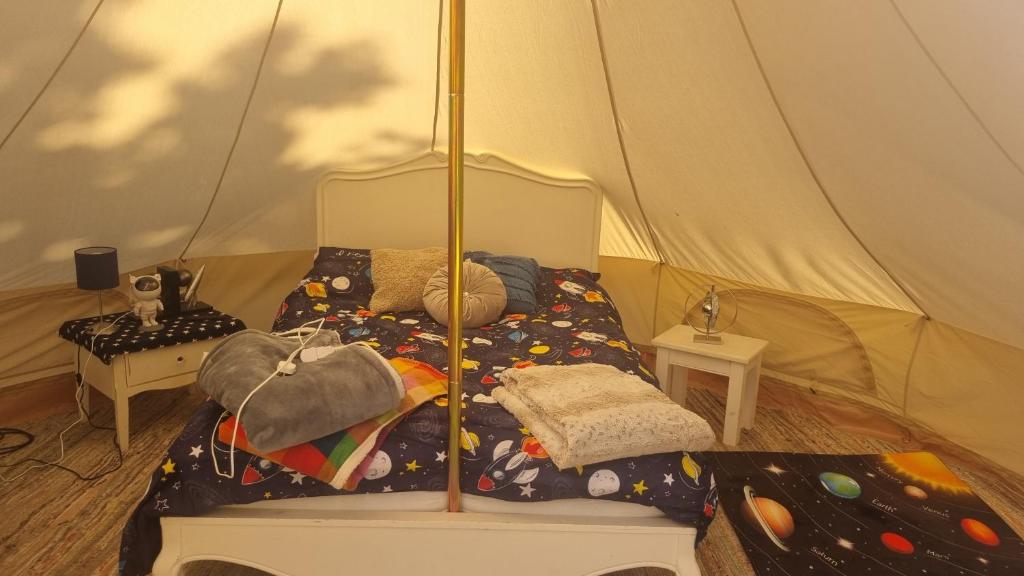 a bed in a tent in a room at Stargazer bell tent secret garden glamping 