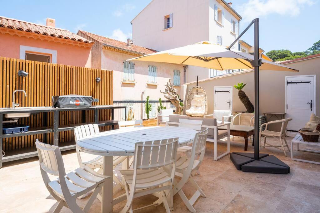 a patio with a table and chairs and an umbrella at Ile de Porquerolles, KerMarc, appartement lumineux avec grande terrasse in Porquerolles