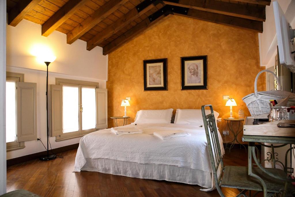 a bedroom with a large white bed and two windows at B&B Casa del Teatro in Mantova