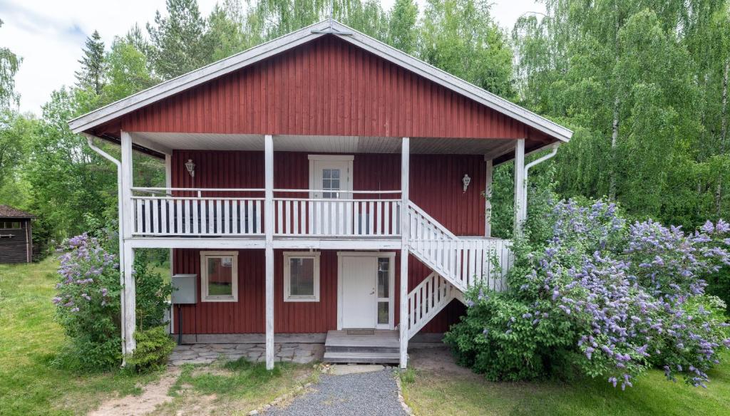 une maison rouge avec une véranda blanche et des fleurs dans l'établissement Selmas Gård, à Östra Ämtervik