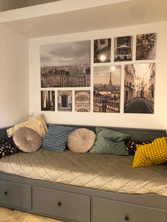 una camera con un divano e immagini appese al muro di Paris-Eiffel, bienvenue -terrasse -Netflix a Pantin