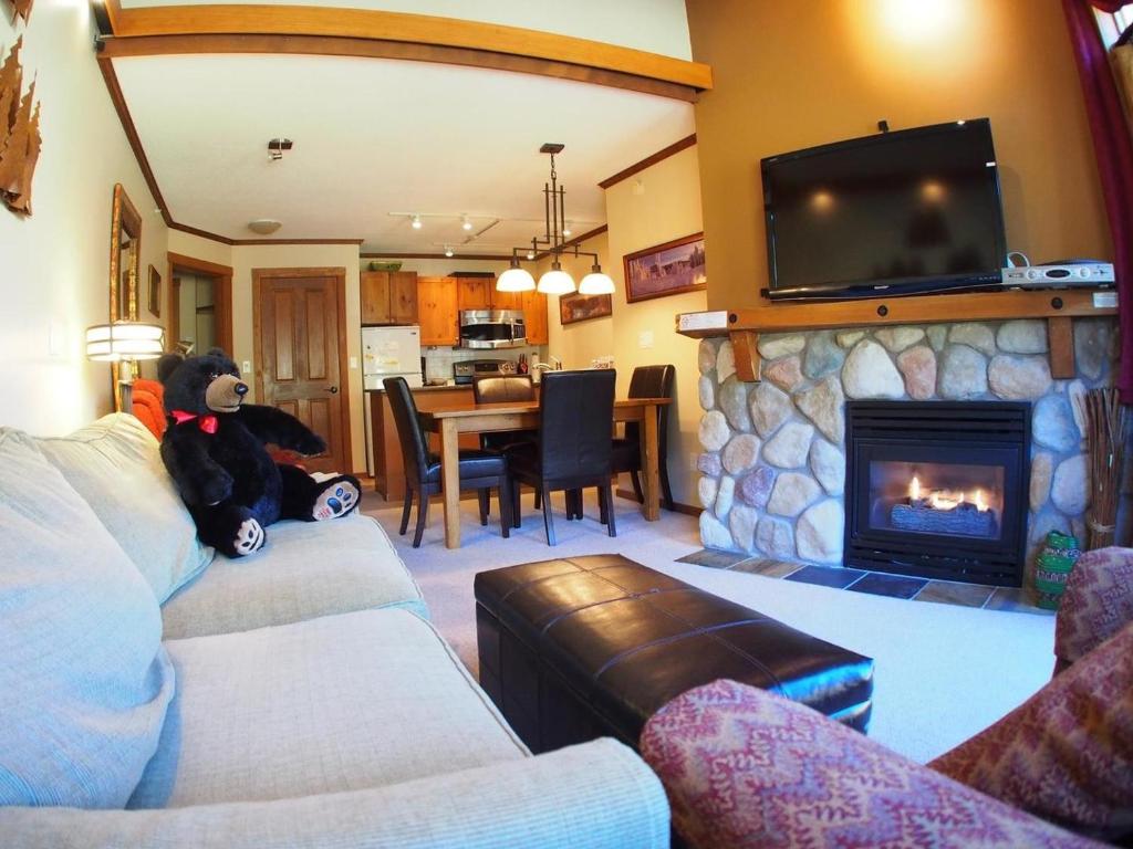 a teddy bear sitting on a couch in a living room with a fireplace at Fireside Lodge #409 By Bear Country in Sun Peaks