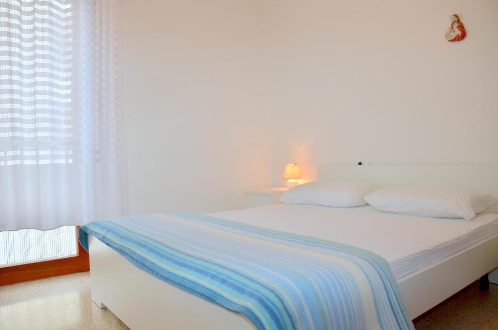 a white bed with a blue and white blanket on it at Condominio Al Mare in Bibione
