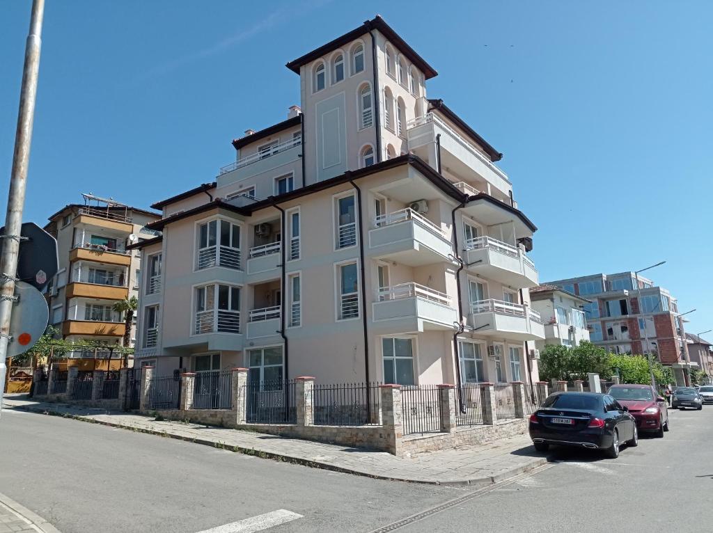 a tall white building with cars parked in front of it at Екзарх Йосиф in Tsarevo