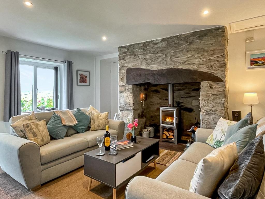 a living room with two couches and a stone fireplace at Hyfrydle Cottage in Pen-y-groes