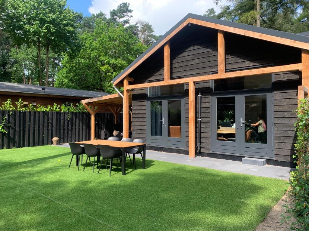 DoornspijkにあるVakantiehuis Veluws Genieten met whirlpool en saunaの庭のテーブルと椅子付きの家