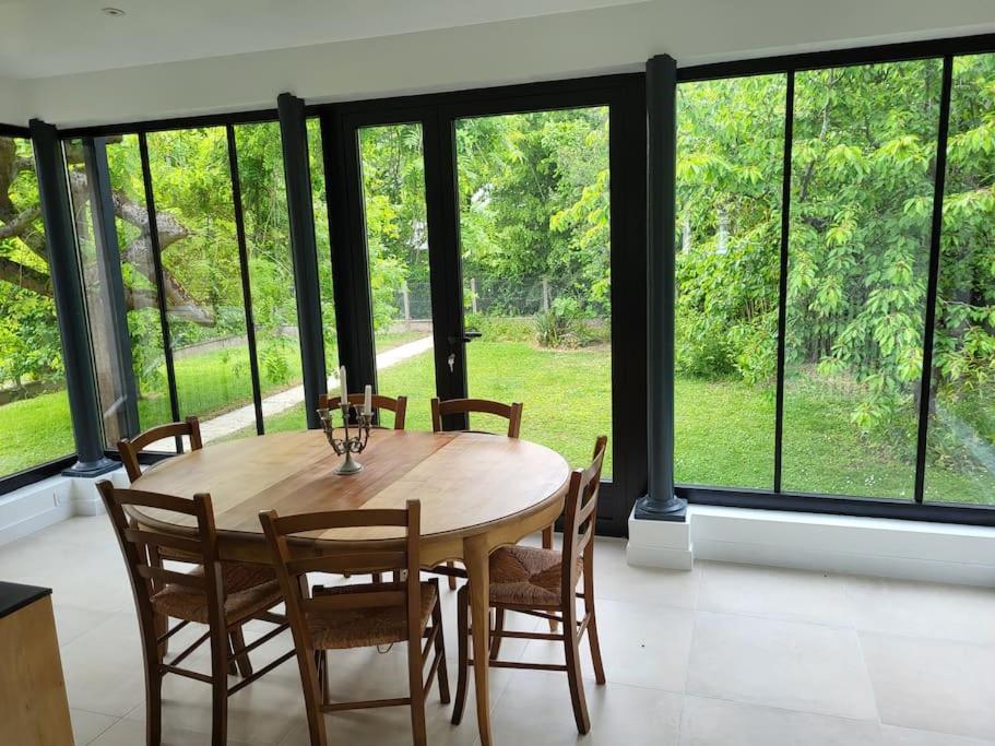 einen Holztisch und Stühle in einem Zimmer mit Fenstern in der Unterkunft La maison des Sablons in Chartres