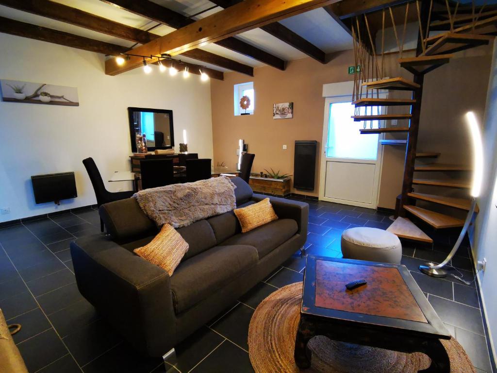 ein Wohnzimmer mit einem Sofa und einer Wendeltreppe in der Unterkunft Le Gai Lo Gite in Villers-Pol
