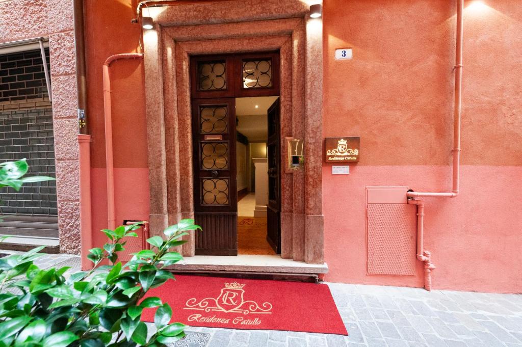eine Tür zu einem Gebäude mit einem roten Teppich davor in der Unterkunft Residenza Catullo - Apartments in Verona