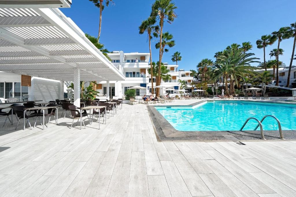 a swimming pool with tables and chairs next to a building at BLUESEA El Dorado in Puerto del Carmen
