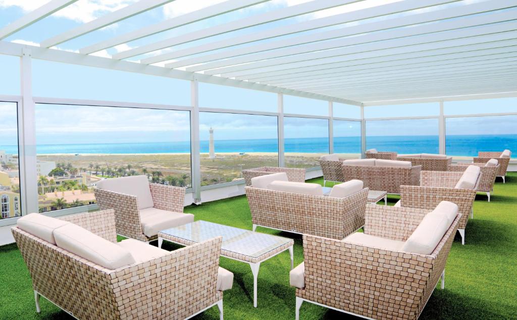 eine Terrasse mit Stühlen und Tischen und Meerblick in der Unterkunft FERGUS Cactus Garden in Playa Jandia