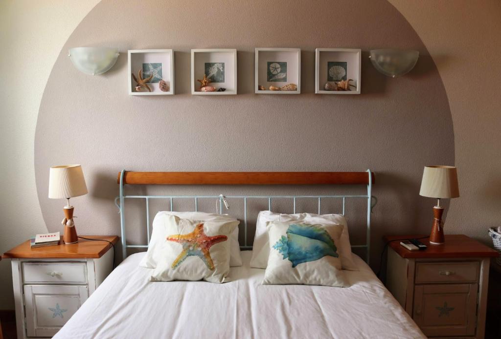 ein Schlafzimmer mit einem Bett mit drei Bildern an der Wand in der Unterkunft Starfish Beach House in São Pedro de Muel