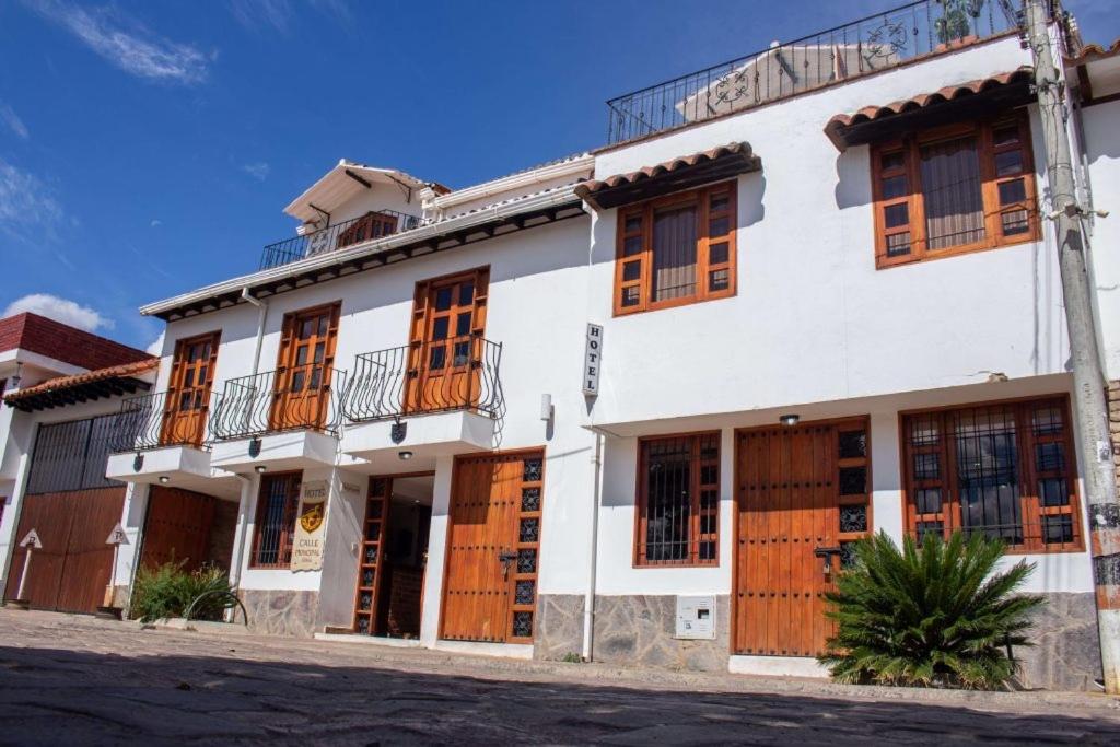 - un bâtiment blanc avec des portes et des fenêtres en bois dans l'établissement Hotel Calle Principal, à Sáchica