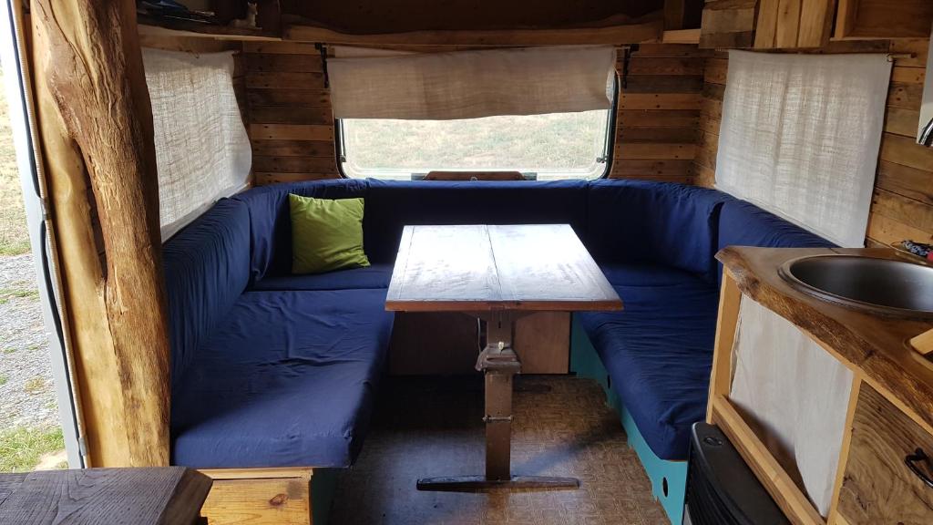 - un canapé bleu dans une petite maison avec une table dans l'établissement la cabane mobile, à Beyssenac