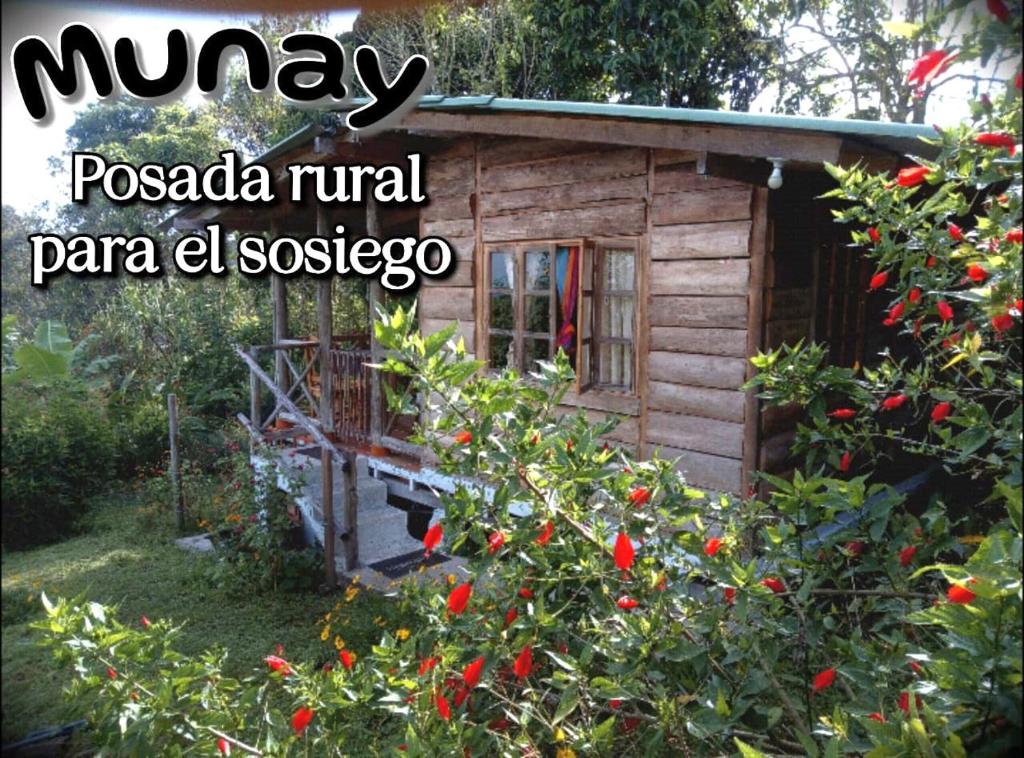 Cabaña de madera pequeña con un arbusto con flores rojas en MUNAY, Posada rural para el sosiego en Alcalá