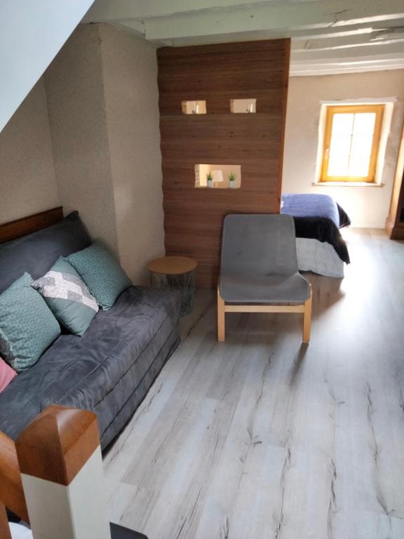 Zimmer mit einem Sofa, einem Bett und einem Stuhl in der Unterkunft La Brousse Kacha in Malleret-Boussac
