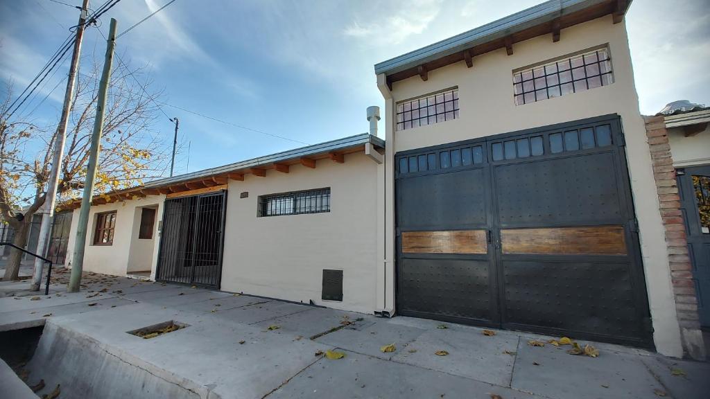 una casa blanca con una puerta de garaje negra en DON ALBERDI ALOJAMIENTOS en San Rafael