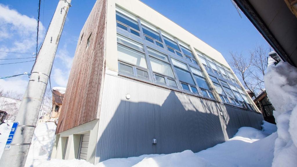 un edificio en la nieve junto a un poste en Full Circle Apartments, en Niseko
