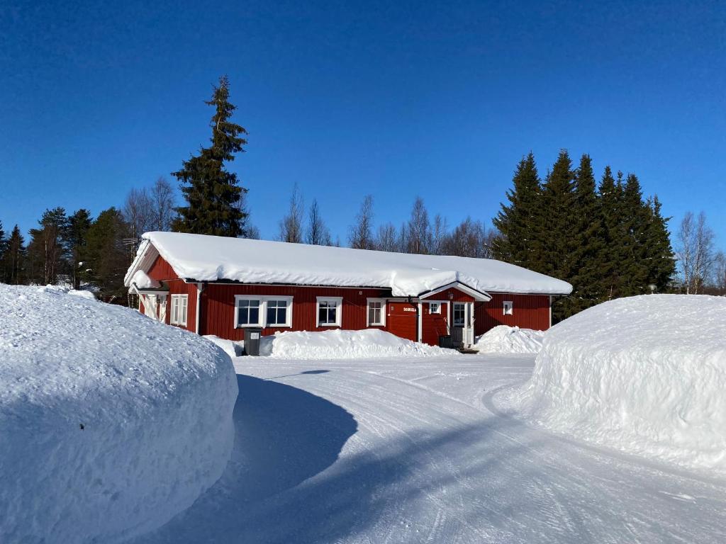 un granero rojo con nieve en el suelo junto a una carretera en Soukolo Apartments en Äkäslompolo