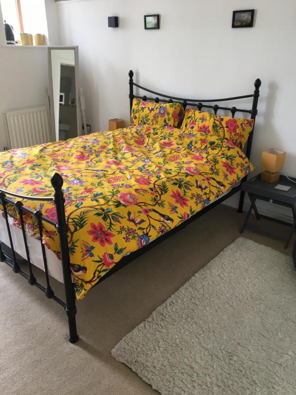 a bedroom with a bed with a yellow floral bedspread at Double Room with en-suite shower and juliet balcony in Rossendale