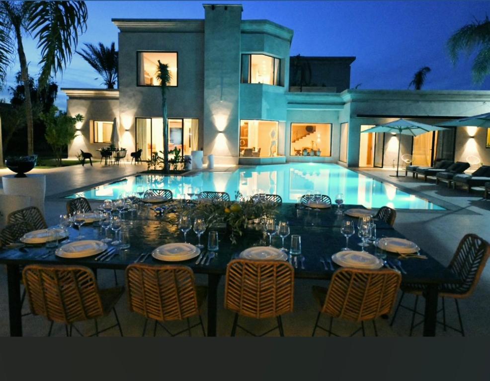a table with chairs and wine glasses in front of a house at LUXURY VILLA 7 in Marrakesh