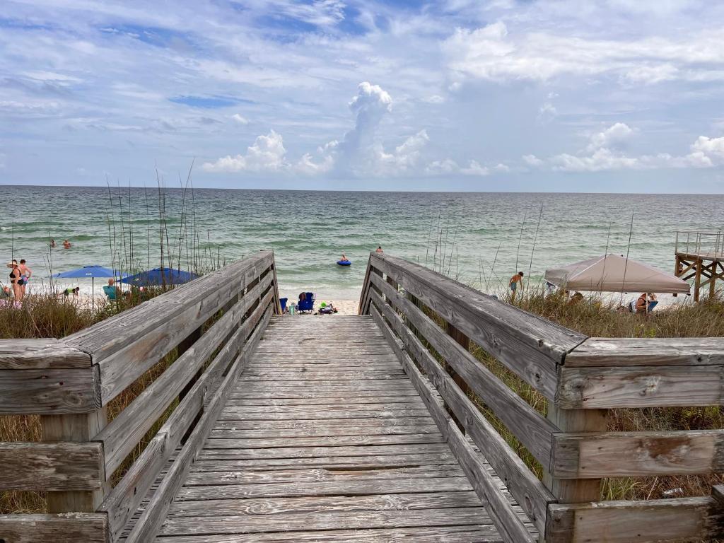 a wooden boardwalk leading to a beach with people on it at Glimpse of Grace at the Bay in Gulf Shores