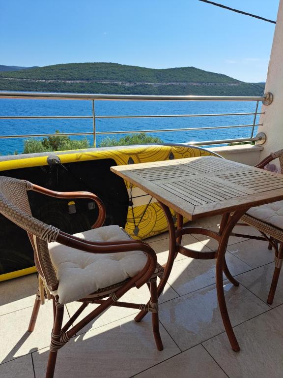 a wooden table and chairs on a balcony with the ocean at Ana in Neum