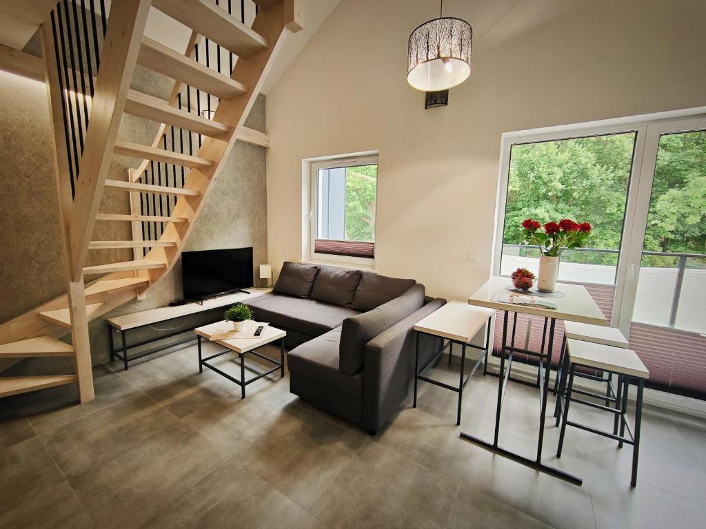ein Wohnzimmer mit einem Sofa und einem Tisch in der Unterkunft M&K Apartament Magiczny Las, Gdańsk - Wyspa Sobieszewska in Danzig