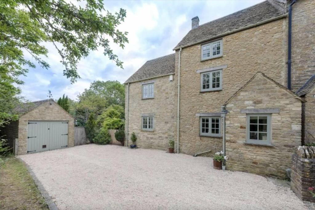 an exterior view of a brick house with a driveway at Charming 3-Bed Cottage near Chipping Norton in Chipping Norton