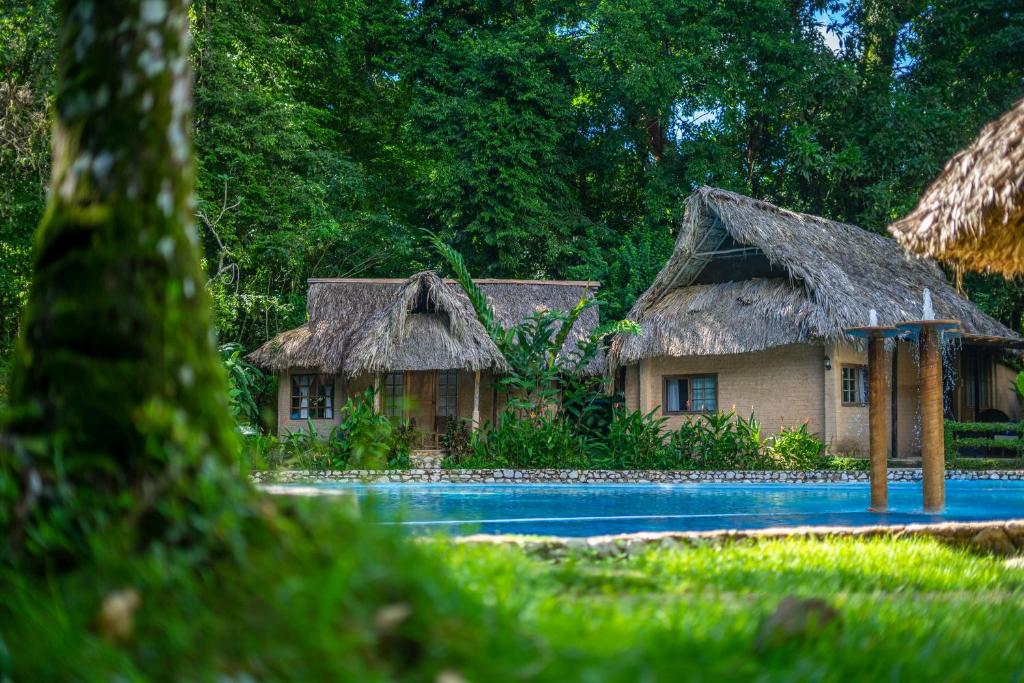 um resort com uma piscina e duas cabanas em Hotel Maya Bell em Palenque