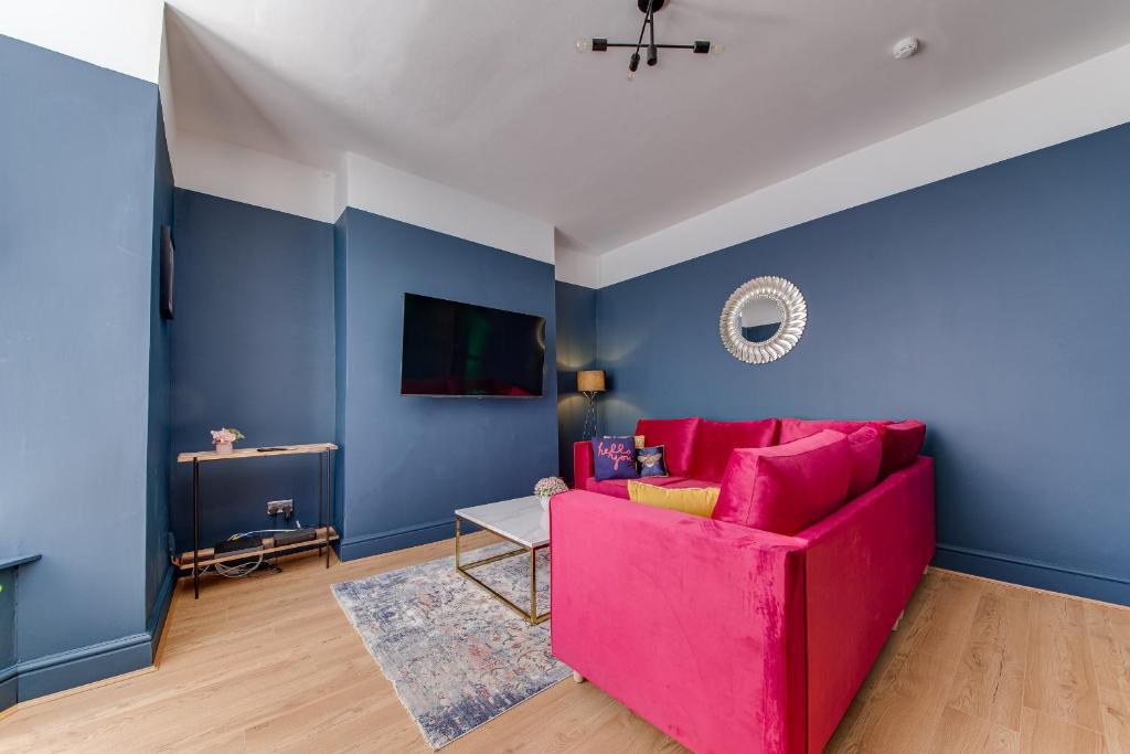 sala de estar con sofá rosa y paredes azules en Air Host and Stay - Rockfield Lodge, sleep 12 free parking next to LFC en Liverpool