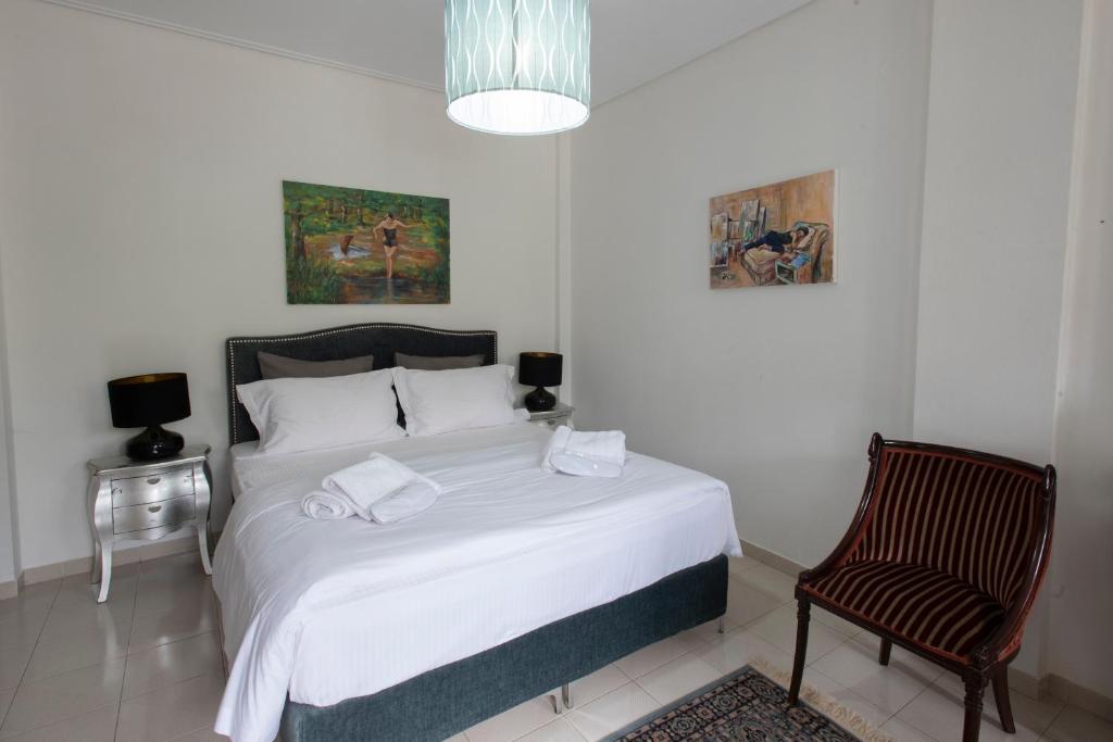 a bedroom with a large white bed and a chair at Met & Kas corner spacious house with countryard in Volos