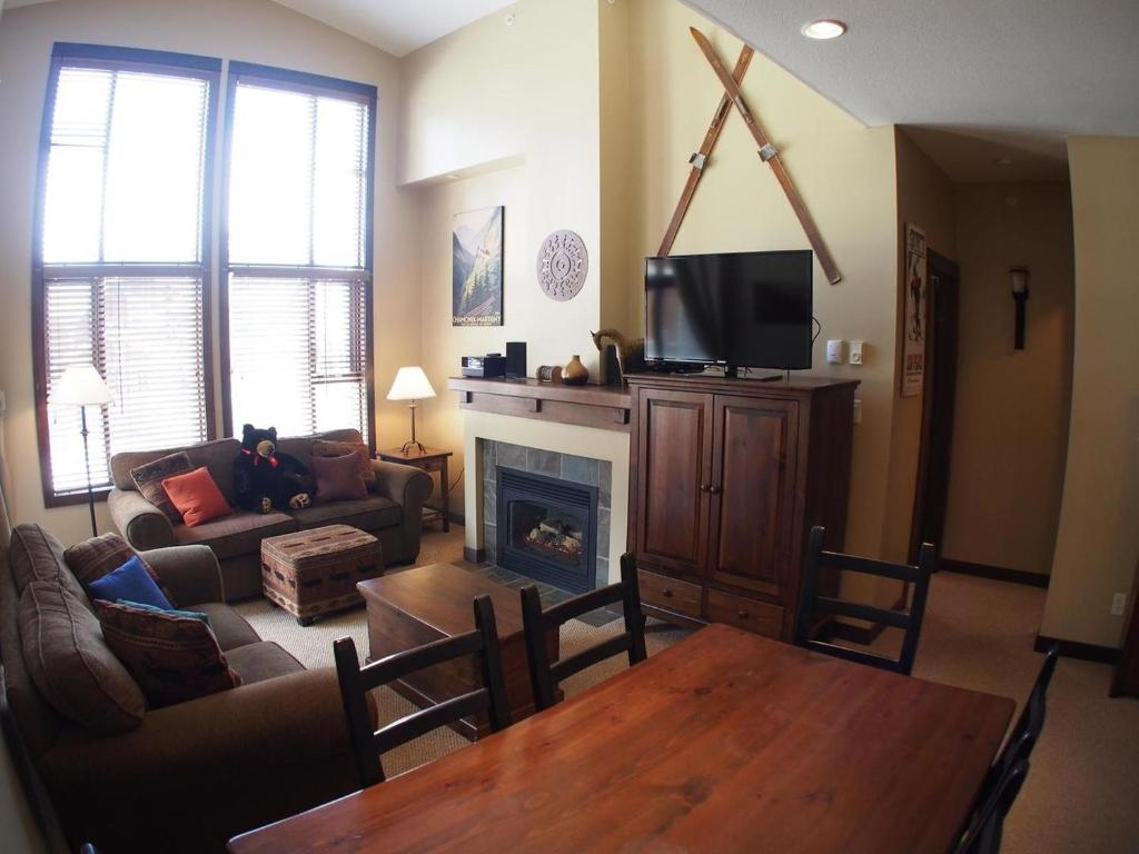 a living room with a couch and a table and a tv at Stones Throw #38 By Bear Country in Sun Peaks