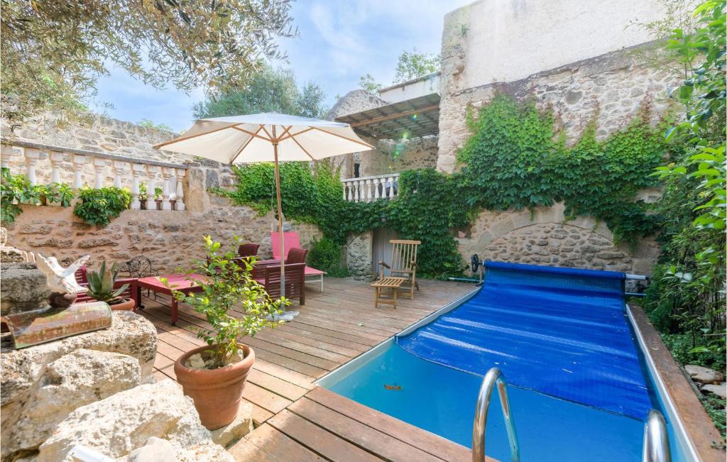 un patio trasero con piscina azul y sombrilla en 2 Bedroom Beautiful Home In Montbazin, en Montbazin
