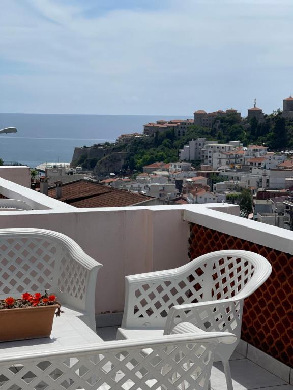 two white benches sitting on a balcony overlooking a city at Apartments Milla in Ulcinj