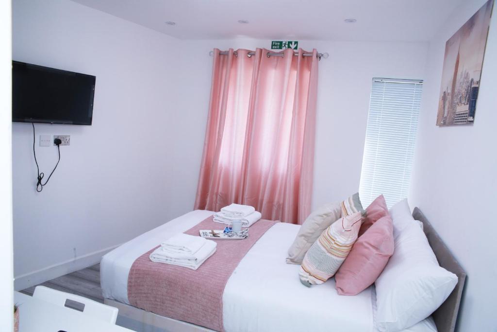 a bedroom with a bed with pink curtains and a television at Harrow Luxury flat With free parking. in London