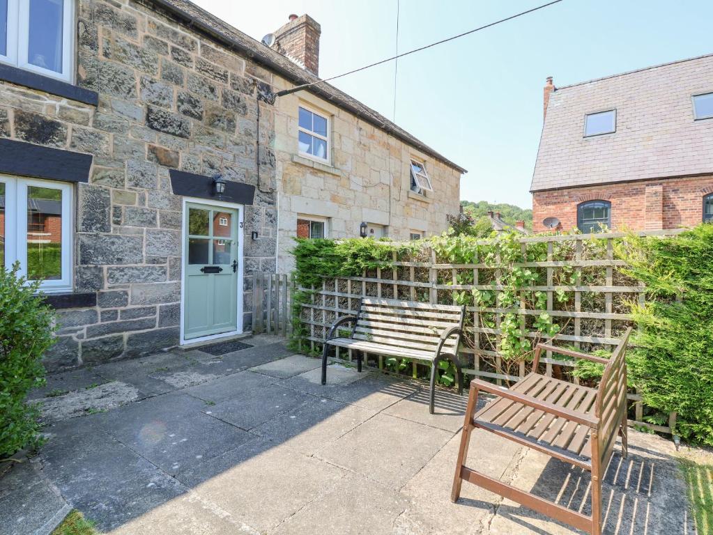 un banc en bois assis devant un bâtiment en pierre dans l'établissement Carreg Cottage, à Wrexham