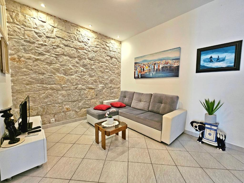 sala de estar con sofá y pared de piedra en Apartments Moni, en Split