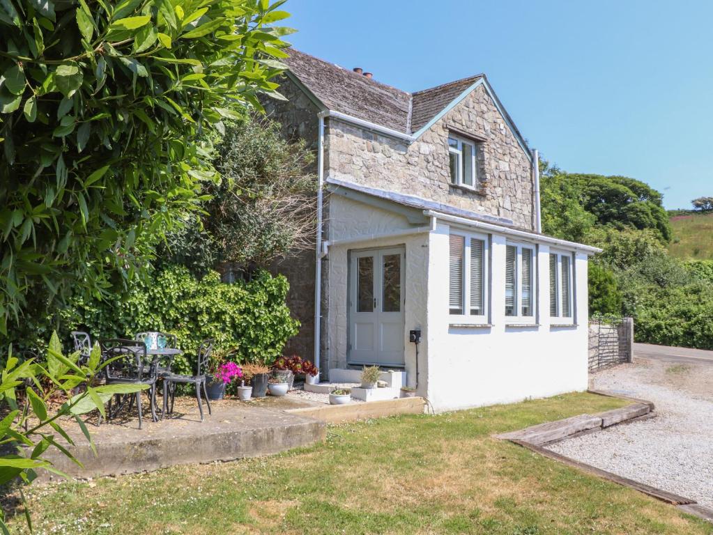 una cabaña con mesa y sillas frente a ella en Rockhopper Cottage en Penzance