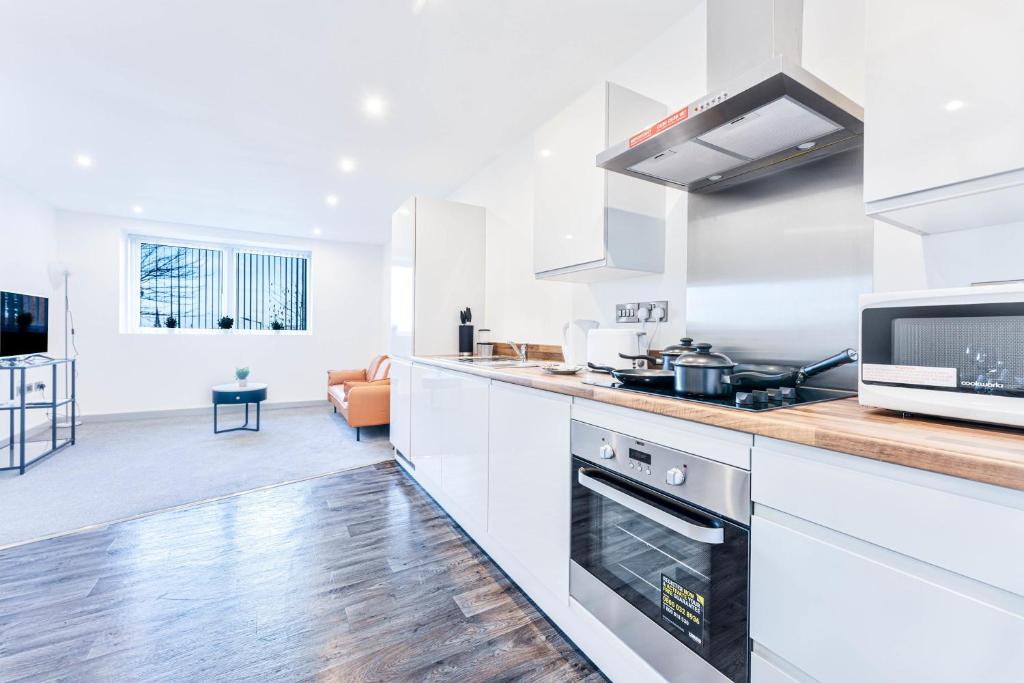 a kitchen with white appliances and a living room at Stylish 1 Bed Apartment in Wolverhampton in Wolverhampton