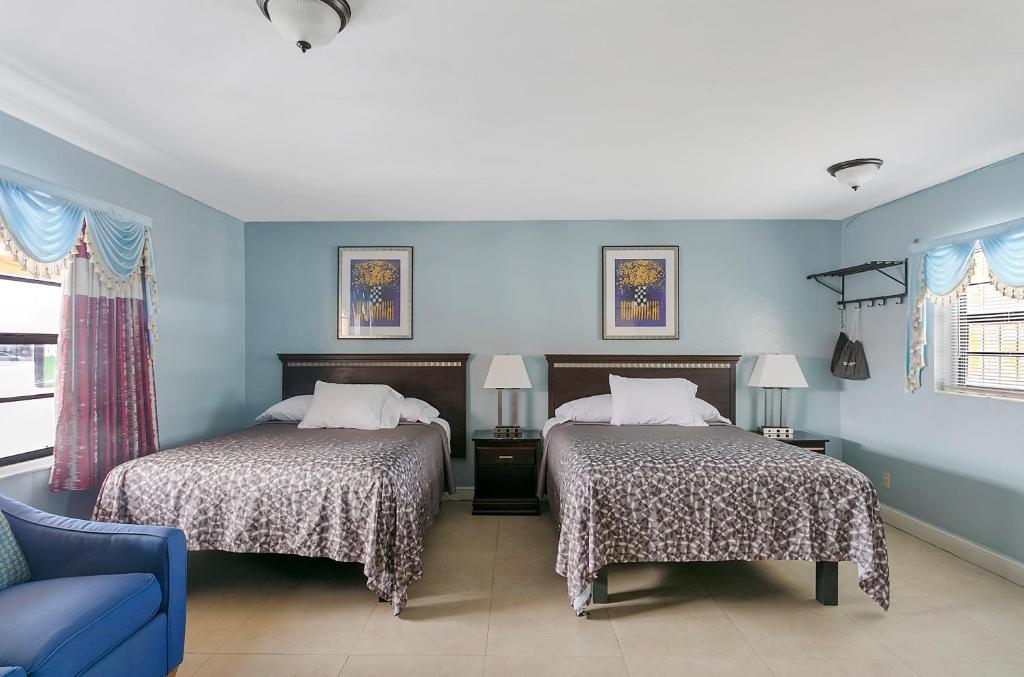 two beds in a room with blue walls at Deluxe Inn in Dania Beach