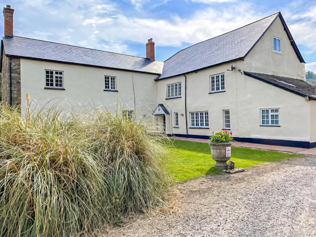 Duvale Priory - 9985 في Bampton: منزل أبيض كبير مع ساحة مع عشب طويل