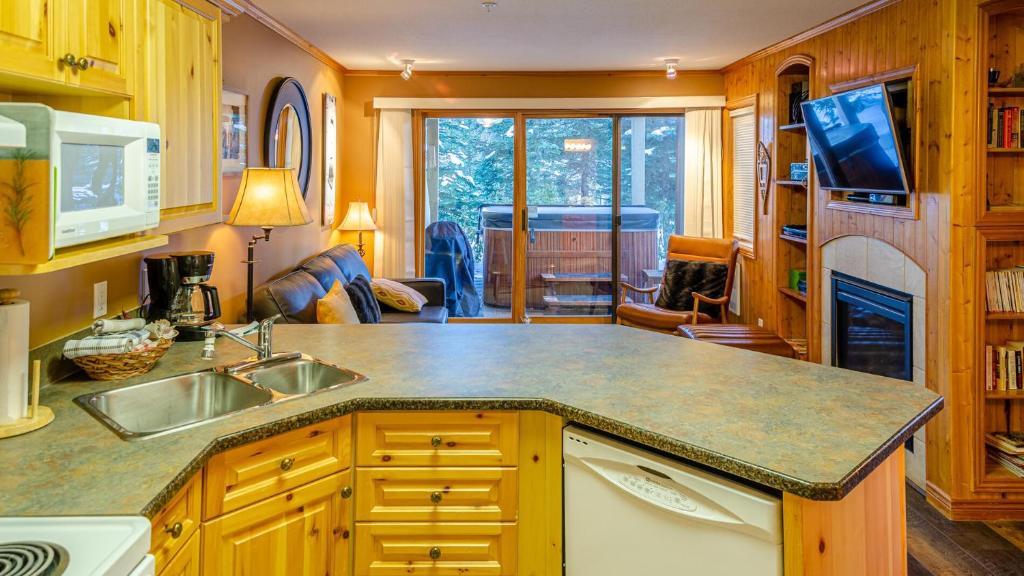 uma cozinha com um lavatório e uma sala de estar em Snow Creek Village #48 By Bear Country em Sun Peaks