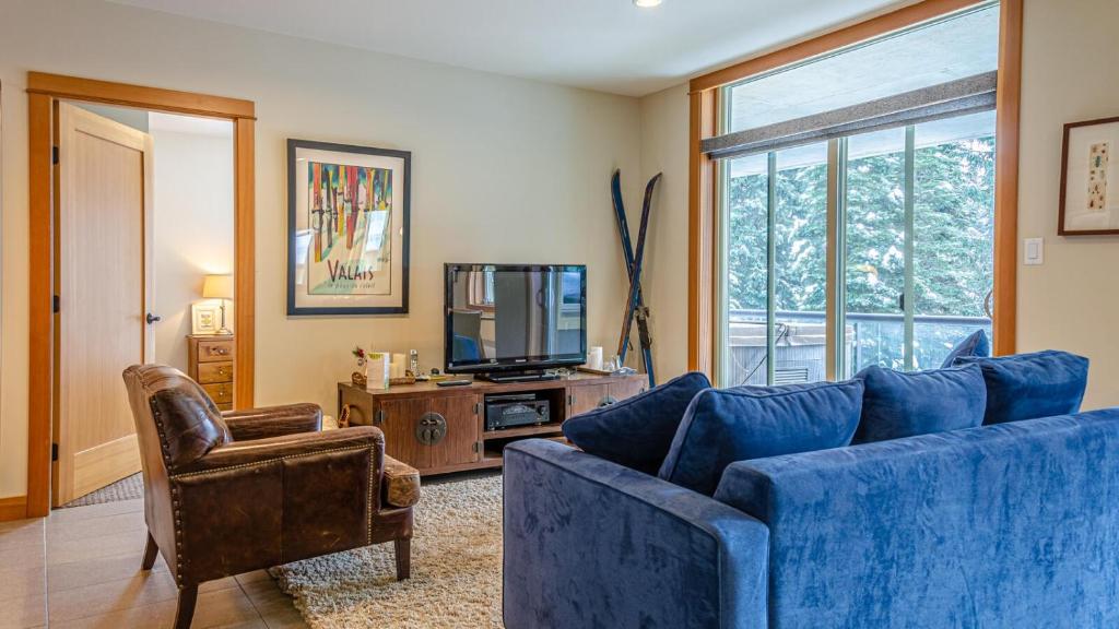 un salon avec un canapé bleu et une télévision dans l'établissement Kookaburra Lodge #303 By Bear Country, à Sun Peaks