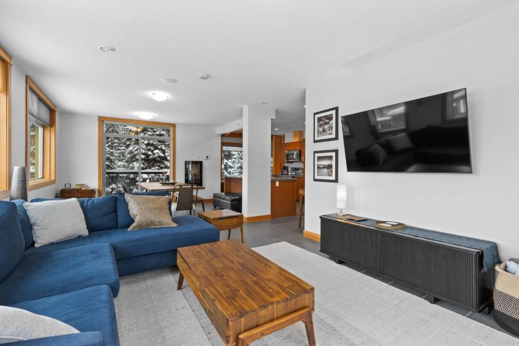 een woonkamer met een blauwe bank en een tv bij Kookaburra Lodge #203 By Bear Country in Sun Peaks