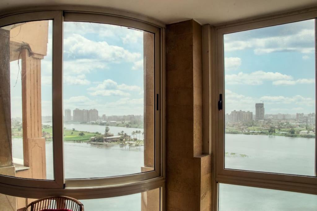 a room with two windows with a view of the water at LuxuryApartmentDirectToTheNile in Cairo