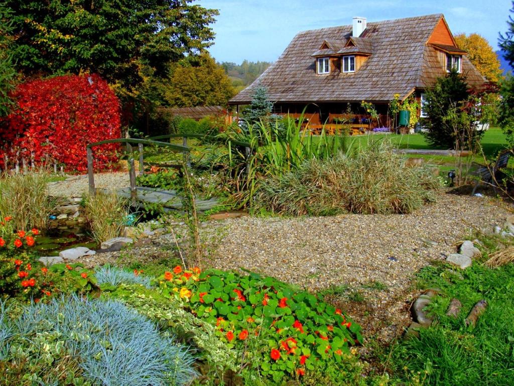 a garden with flowers and a house in the background at Noclegi U Lestka in Lutowiska