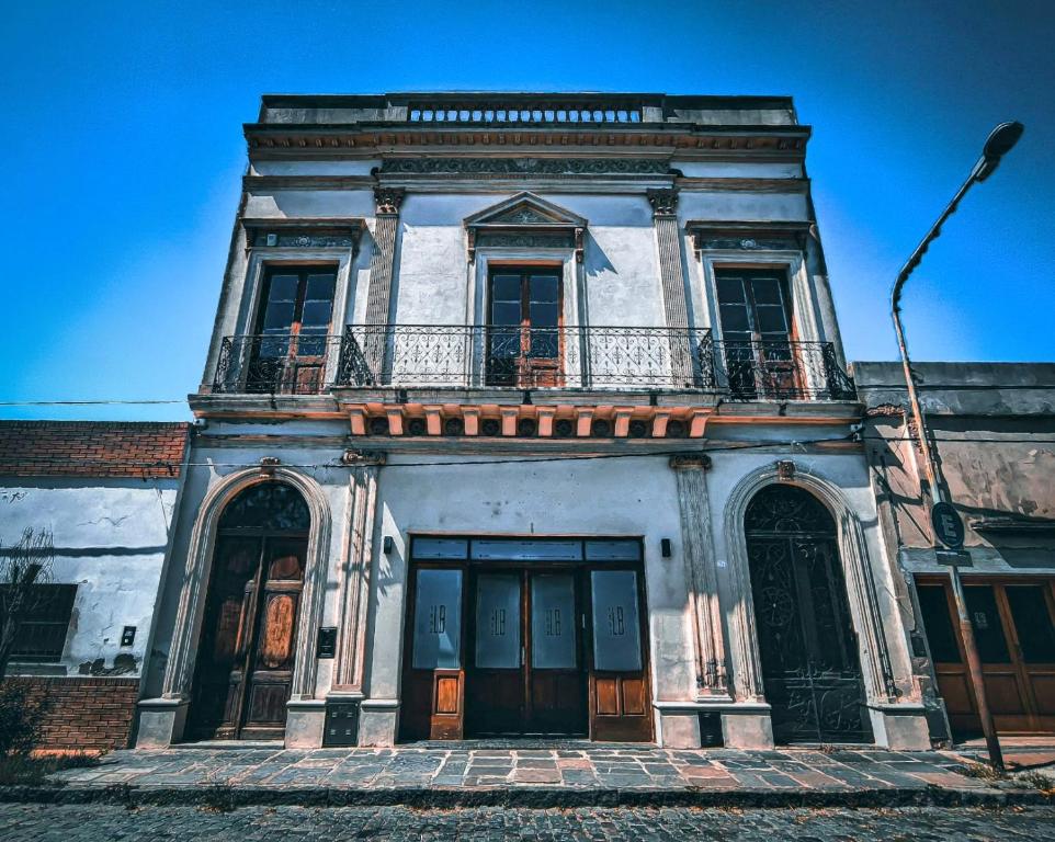 um edifício antigo com uma varanda em cima em La Botica de 1852 Hotel em Chascomús