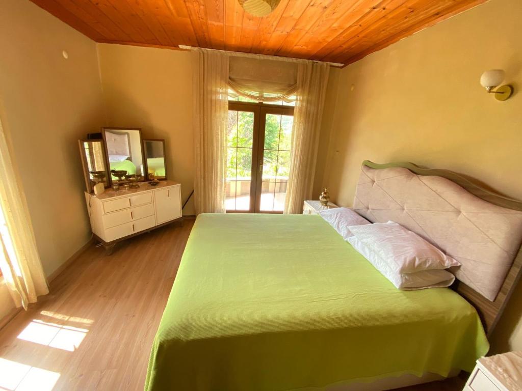ein Schlafzimmer mit einem grünen Bett und einem Fenster in der Unterkunft MOUNTAIN HOUSE in Trabzon